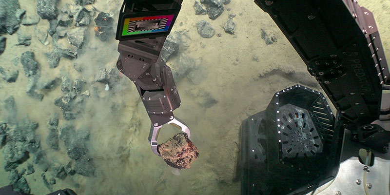 A rock being collected by the arm of the ROV.