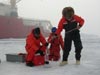 Scientist lower containers through a hole in the ice to collect water samples from different depths.