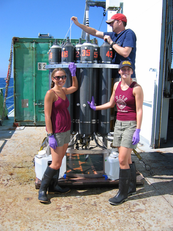  Christine Desautels and Monica Heintz work with research technician Nathan Buck to extract water samples from a recently recovered CTD/Niskin Rosette cast containing plume water samples.