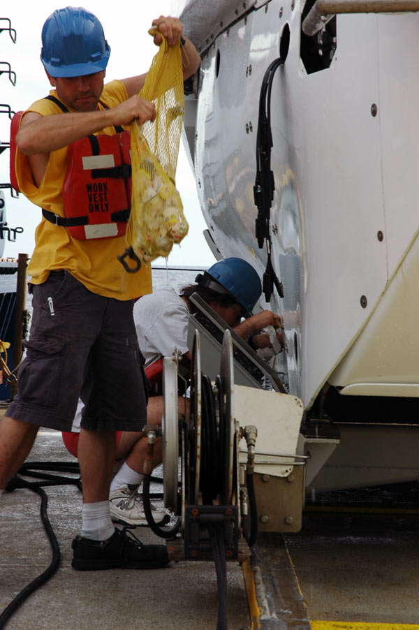 ALVIN Pilot-in-Training Anton Zafereo carefully removes a bag of shrunken Styrofoam cups destined for use by educators and students around the Nation.