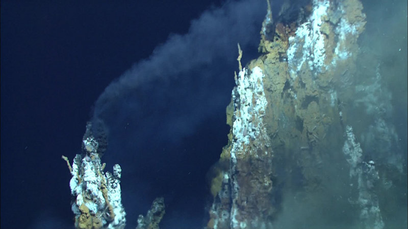 Black smoke from the top of a chimney is carried “downward” by the strong current in the vent field.