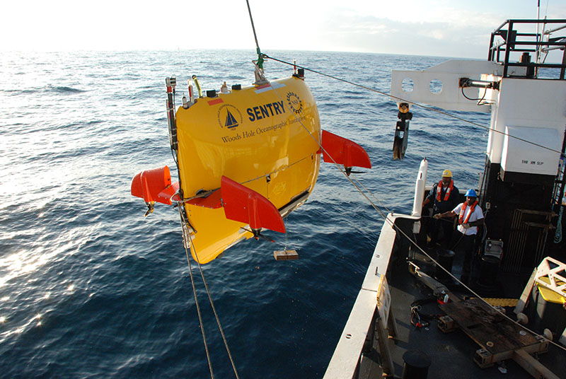 The Pisces deck crew and the Sentry engineers work together to hold the taglines seen here connected to the Sentry. The taglines are used to steady the Sentry while the crane lifts it off the deck and over to the water.