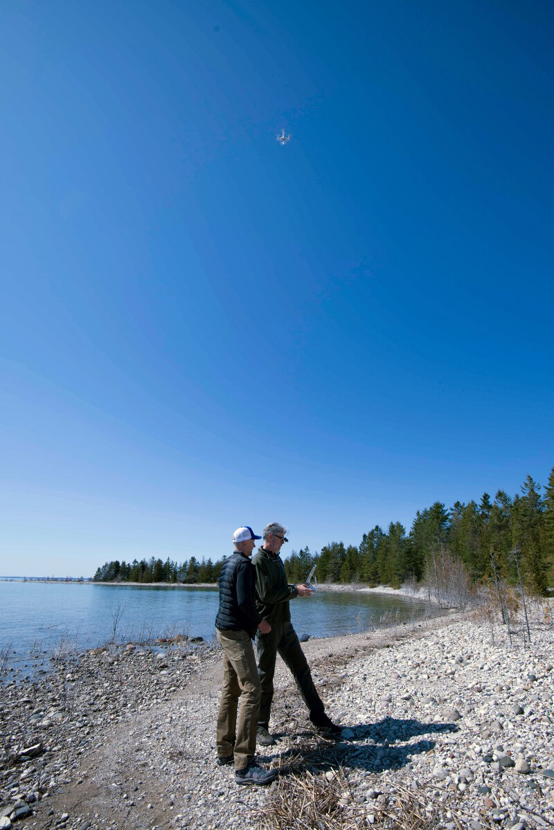 Pilot Brian Taggart controls a Phantom 4 quadcopter (hovering above) as pilot Matt Pickett observes.