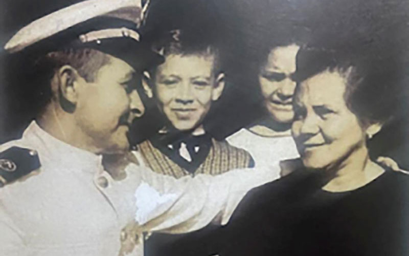 A vintage photo of a naval officer with three family members.