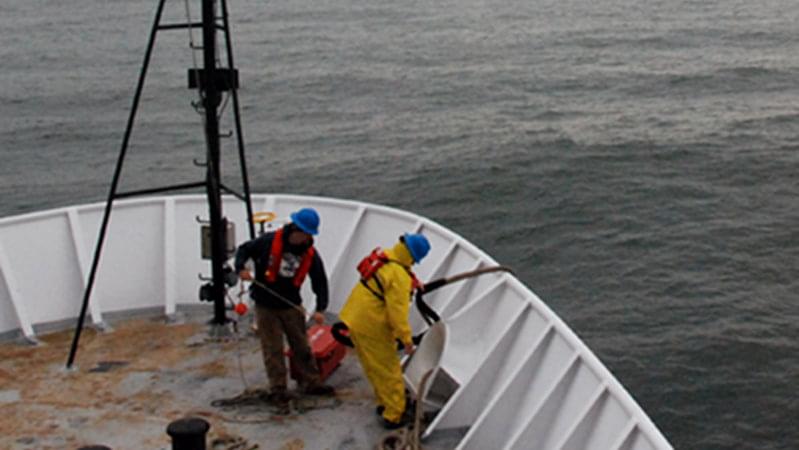 Two deck hands prepare <em>Okeanos Explorer</em> to come into port as she nears the Golden Gate Bridge. The EX1006 “Always Exploring” cruise ended today when the ship came into port in San Francisco harbor.