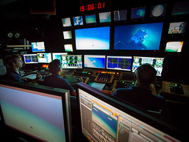 Bobby Mohr (left) and Jeff Williams (right) provide guidance during Anthony Sylvester's first experience as an ROV pilot.