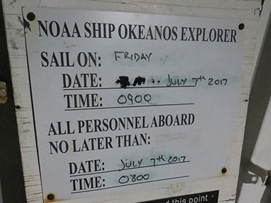 Picture of the sailing board on NOAA Ship Okeanos Explorer showing the date and time of departure for the next cruise and the time by which all personnel who are sailing need to be physically on board the ship to sail. Cruise EX-17-06 departed on time at 0900 on Friday, July 7, as planned.