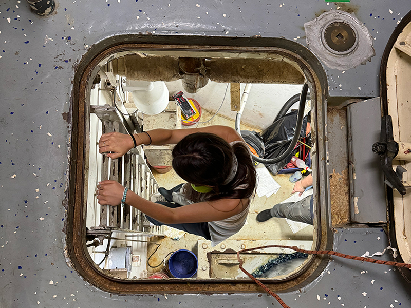 Image of explorer-in-training Anabel climbing down the ladder that leads to a large room with NOAA Ship Okeanos Explorer’s rudder.