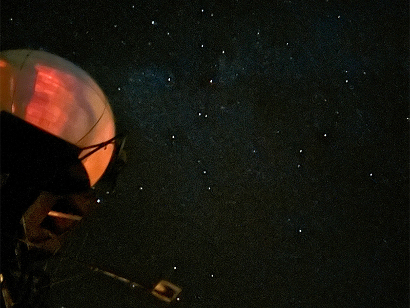 Dome-shaped structure with a reddish glow against a starry night sky.