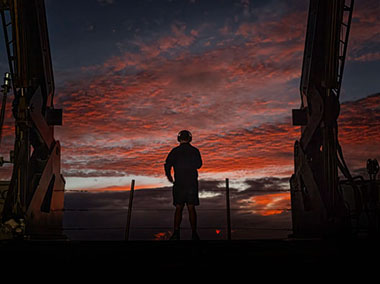 Image of Expedition Coordinator Thomas Morrow checks out the sea and a beautiful sky from the back deck of NOAA Ship Okeanos Explorer.